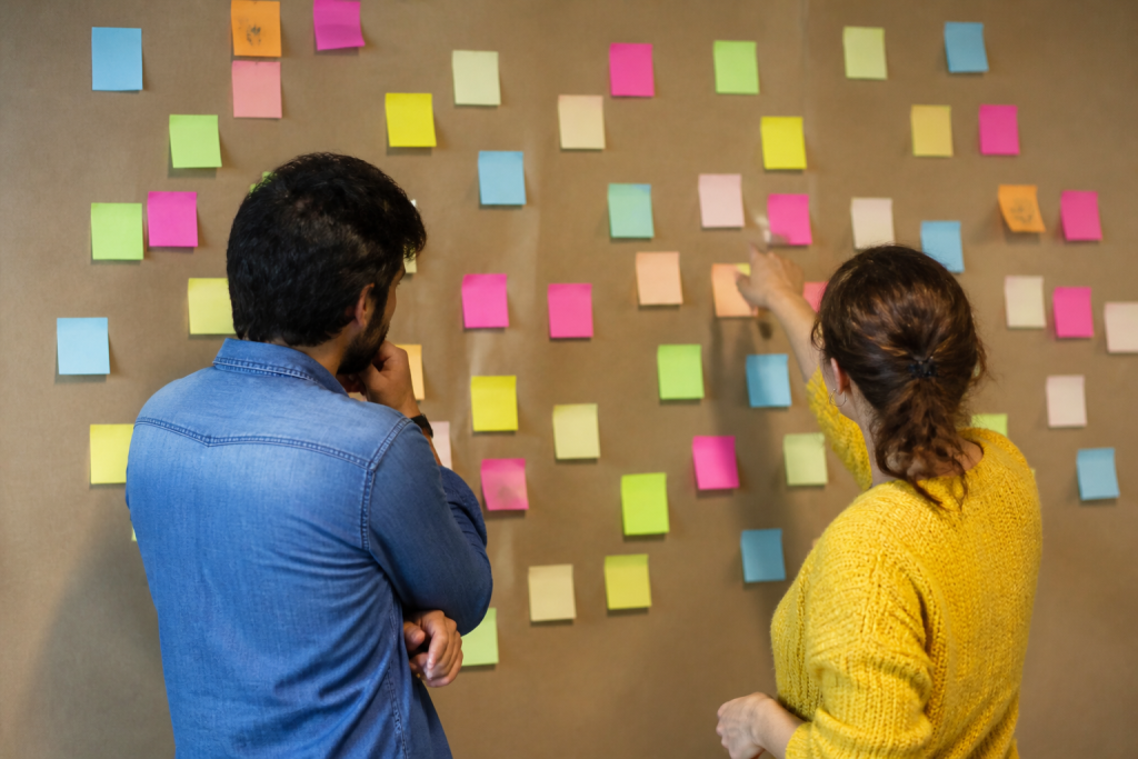 Deux collegues devant un mur couvert de notes colorees