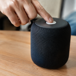 Main appuyant bouton blanc sur enceinte noire